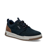 A single low-top casual sneaker shown from a three-quarters angle on a white background. The shoe features a dark navy blue suede upper, dark navy laces, a brown suede heel accent, a thick light gray midsole, and a brown outsole.