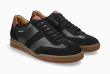A pair of black low-top sneakers with brown gum soles, featuring a mix of leather and suede panels, black laces, and a small white 'MEPHISTO' logo on the side.
